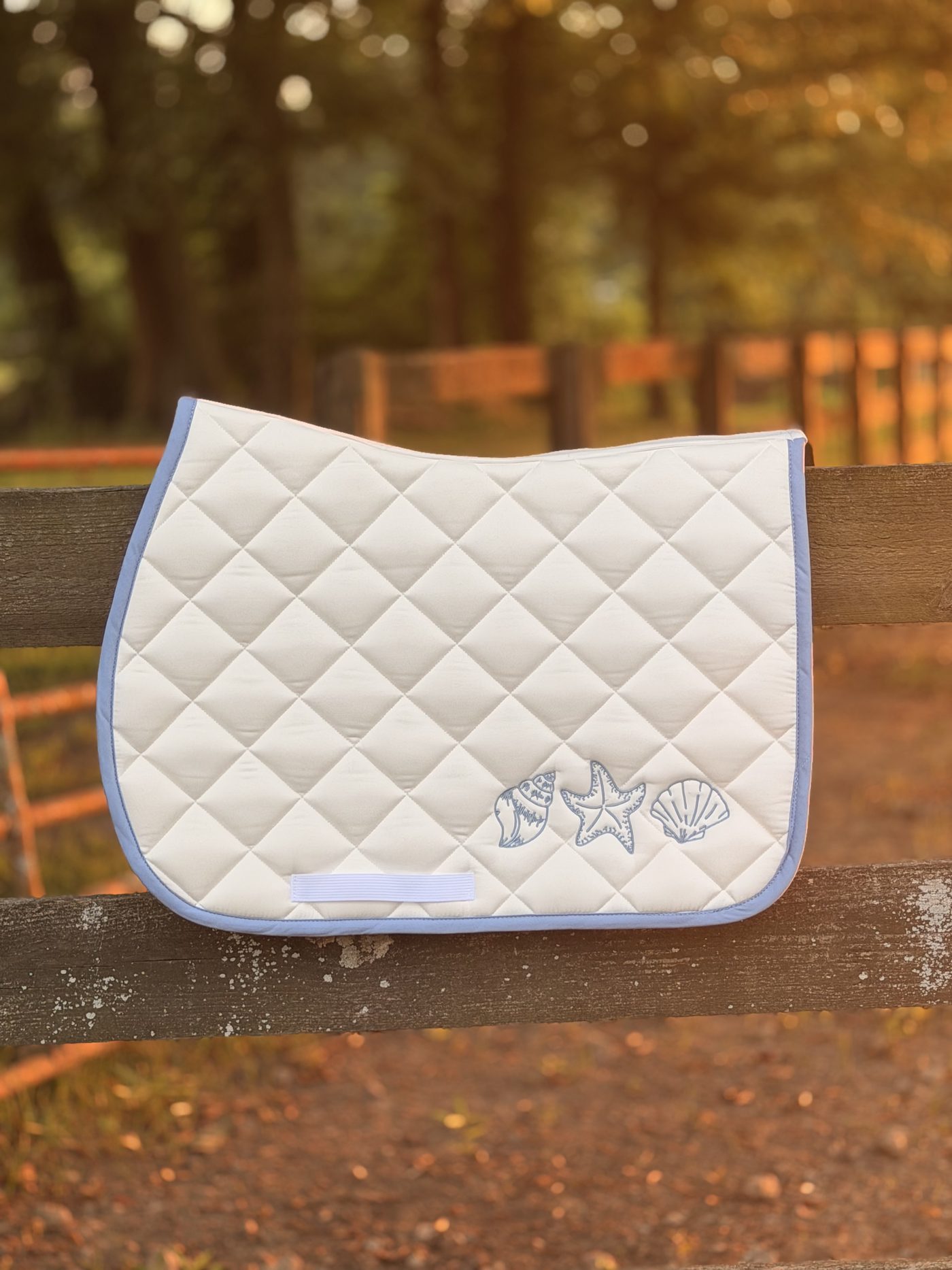 The finished seashell saddle pad from the manufacturer, hung on a fence