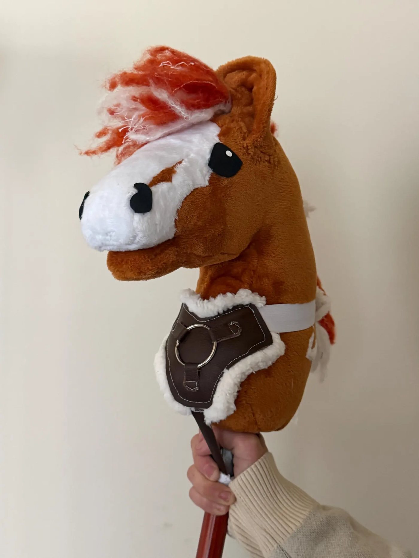 Handmade brown faux-leather breastplate with fleece trim and a silver ring, fitted on a hobby horse