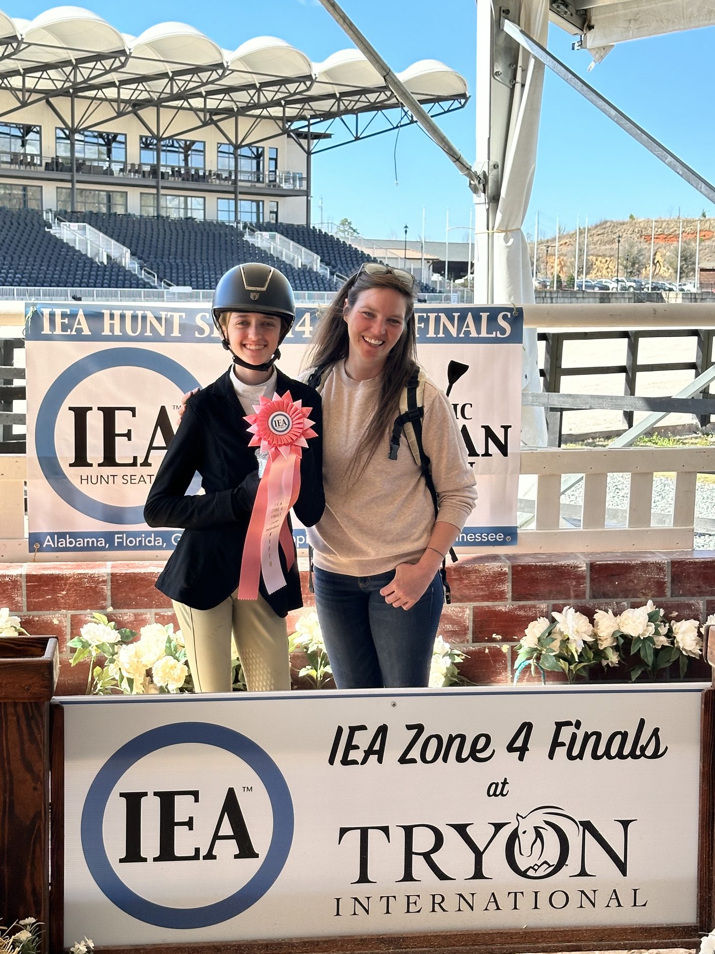 Juliette with her ribbon in front of the IEA Zone 4 Finals sign at Tryon International